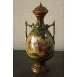A Victorian twin handled hand painted ceramic lidded urn decorated with two female figures and
