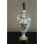 A hand painted armorial crest porcelain twin handled urn lamp with gilded detailing to the square