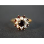 A 9 carat pearl and garnet cluster ring, set with nine round mixed cut garnets with a combined