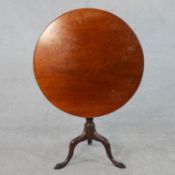 A Georgian mahogany tilt top tripod table with a circular top on a turned and wrythen stem with