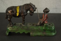 A vintage style painted cast iron mechanical money box of a boy and horse. The horse bucks