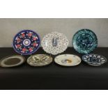 A collection of seven hand painted glazed Continental ceramic platters, each with a different