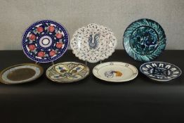 A collection of seven hand painted glazed Continental ceramic platters, each with a different