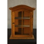 A Dutch style pine wall display cabinet, with an arched top, the door with six glazed panels, with