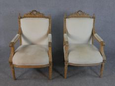 A Pair of French Louis XVI style beech bergere armchairs, with a carved toprail, over open arms