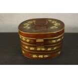 A 19th century toleware hat box, of oval section, parcel gilt and painted with white flowers on a