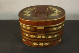 A 19th century toleware hat box, of oval section, parcel gilt and painted with white flowers on a