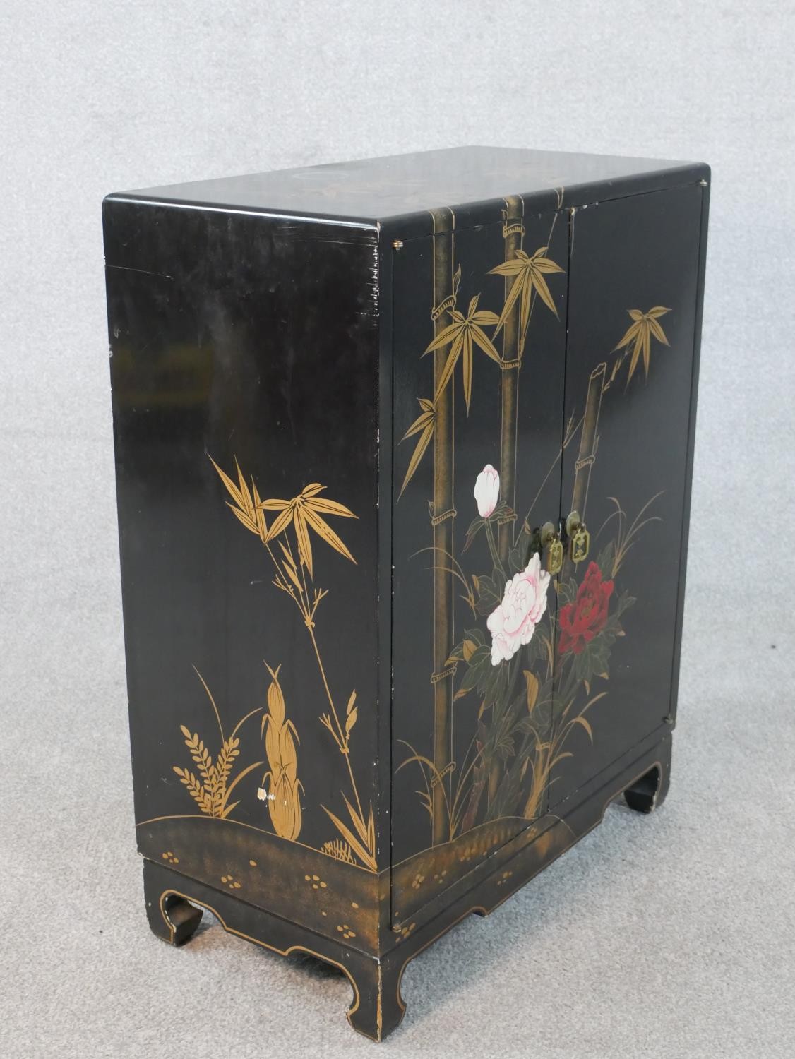 A Chinese peony and bamboo design black lacquered and gilt cabinet with two doors and three - Image 3 of 5