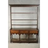 An 18th century oak dresser, the plate rack with three tiers and cup hooks, over three short drawers