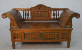 An Indian polychrome hardwood bench with scroll arms and storage section on square tapering