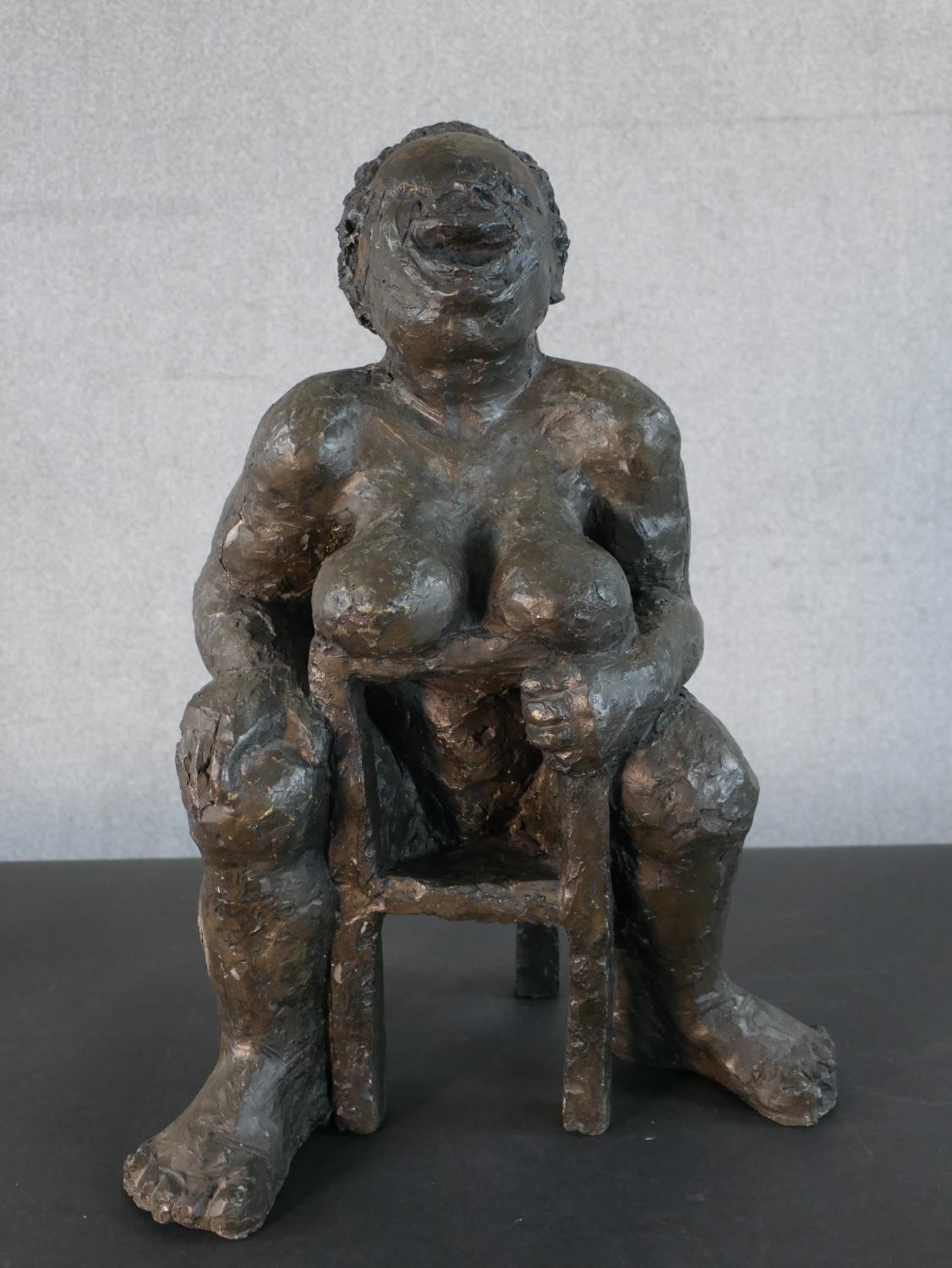 A bronzed moulded figure of a nude woman on a seat laughing, indistinctly signed. H.49 W.36 D.20cm