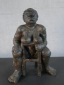 A bronzed moulded figure of a nude woman on a seat laughing, indistinctly signed. H.49 W.36 D.20cm