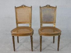 A pair of 19th century Louis XVI style giltwood dining chairs with caned backs and seats and