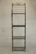 A wrought iron baker's rack of slender form, with four shelves, the sides with S shaped scrolling