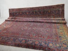 A fine hand woven Persian Sarouk carpet with scrolling foliate decoration across the burgundy