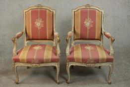 A pair of French Louis XV style grey painted beech fauteuil armchairs, with a ribbon carved crest,