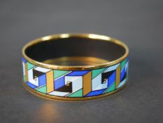 Hermès, a gold plated and enamel blue, green and gold geometric swirl design bangle, makers mark