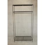 A wrought iron industrial rack, with a rail suspended from below a shelf, over another shelf to