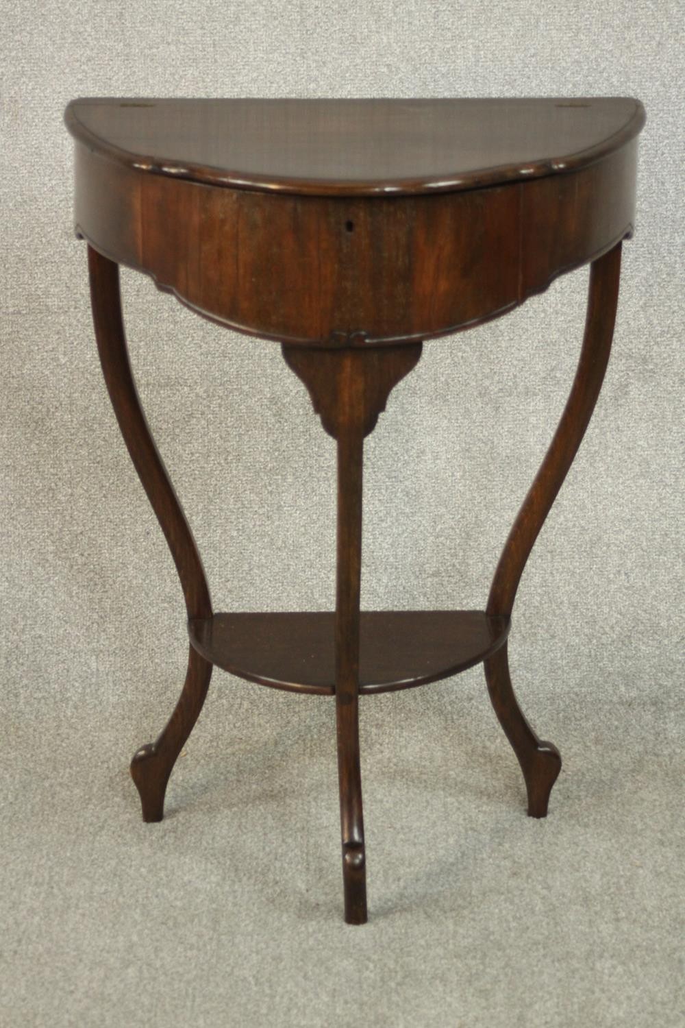 An early 20th century mahogany demi lune side table, with a foldover top opening to reveal a