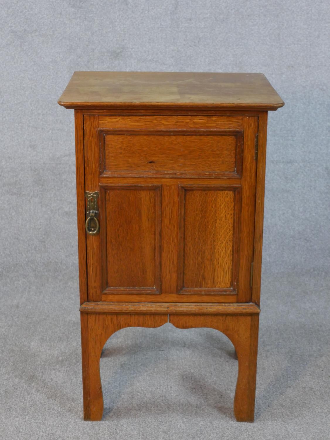 An Arts and Crafts oak bedside cabinet with panel door on shaped supports. H.73 W.45 D.39cm