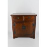 An early 20th century Chinese elm table top cabinet, with two short drawers over two cupboard