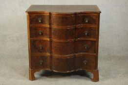 An early 20th century serpentine fronted figured walnut chest of four long graduated drawers with