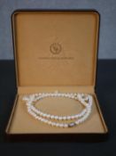 A boxed long string of 116 knotted white round freshwater pearls by Coleman Douglas Pearls,