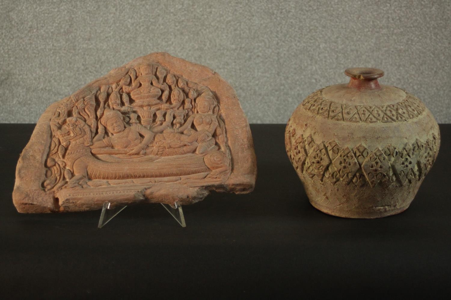 A relief clay tablet depicting Indian deities along with a ceramic vase with incised geometric