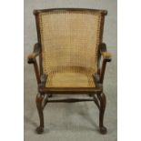 A late 19th century fruitwood open armchair, with a caned curved back and caned seat, on cabriole