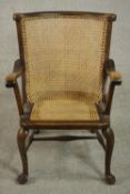 A late 19th century fruitwood open armchair, with a caned curved back and caned seat, on cabriole