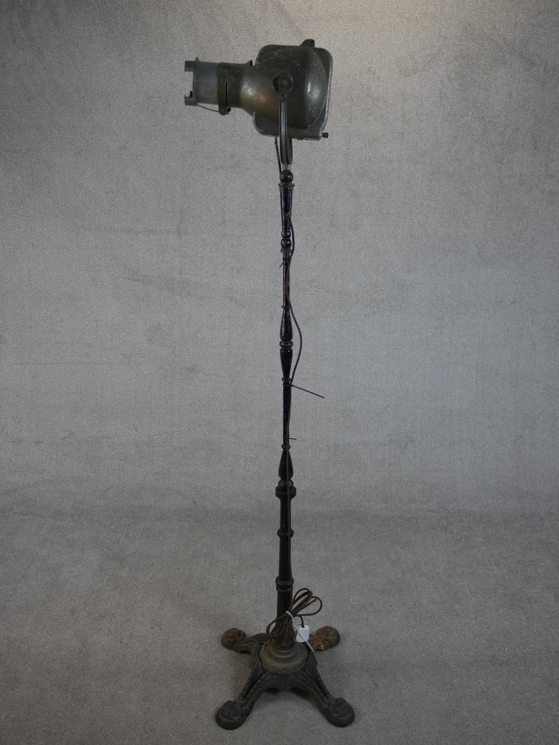 A Strand Electric theatre spotlight, on a cast iron stand. H.190 W.41 D.41cm