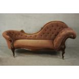 A Victorian walnut chaise longue, upholstered in pink buttoned velour, with a scrolling back and