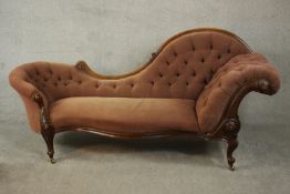 A Victorian walnut chaise longue, upholstered in pink buttoned velour, with a scrolling back and