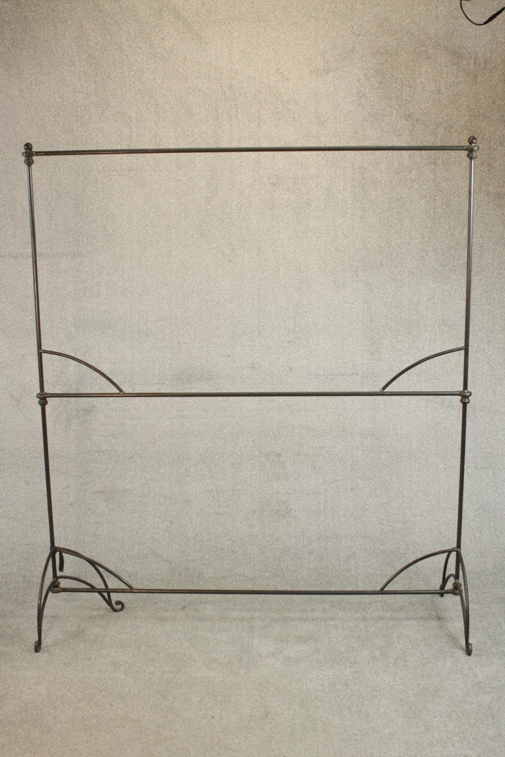 A two tier wrought iron clothes or drying rack. on scrolling legs. (One leg bent) H.176 W.152 D.