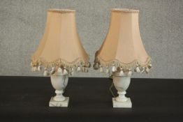 A pair of urn form marble table lamps, on square bases with pink shades. H.38 Dia.20cm. (each)