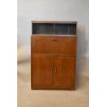A mid 20th century teak secretaire cabinet, the top section with two sliding glass doors over a fall