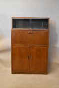 A mid 20th century teak secretaire cabinet, the top section with two sliding glass doors over a fall