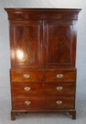 A Georgian mahogany press cupboard the upper section with flame mahogany panel doors enclosing