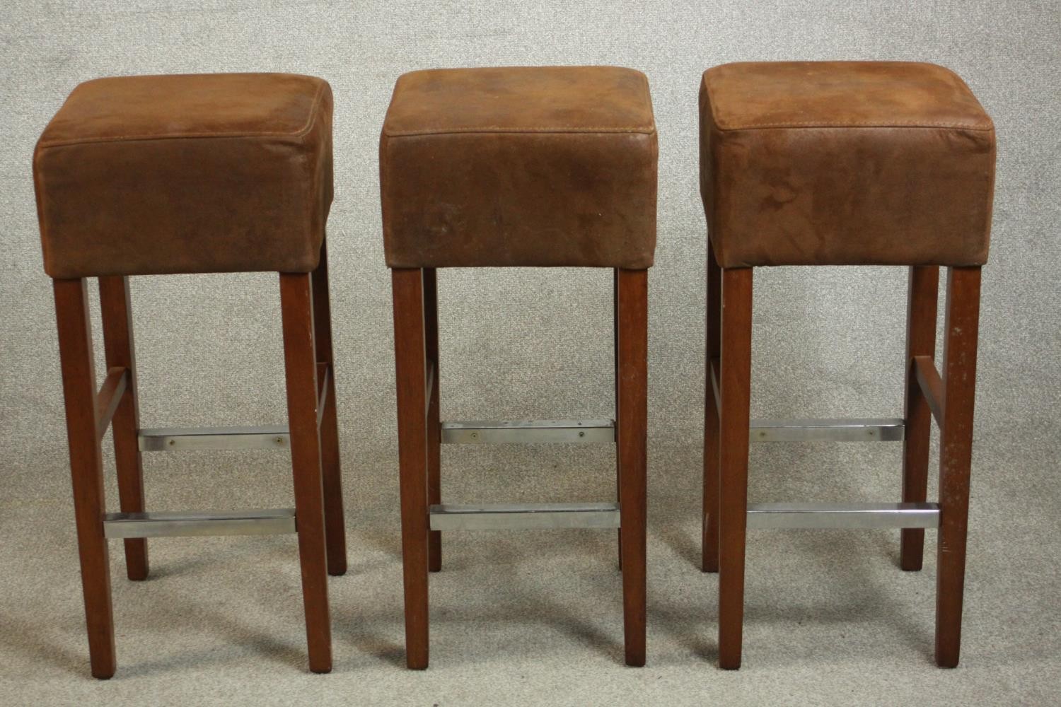 A set of three Andy Thornton contemporary bar stools, with brown suede upholstered seats, on