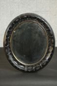 A carved and ebonised wood oval mirror, with a gilt slip and a bevelled mirror plate. H.33 W.29cm.