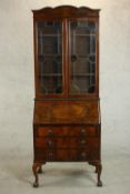 An early 20th century figured walnut bureau bookcase, with two glazed doors enclosing shelves over a