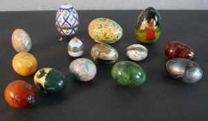 A collection of fourteen eggs, including a ceramic box, hand painted wooden eggs, a Russian