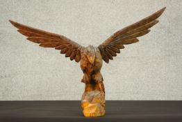 A 20th century carved wood eagle sculpture, with wings spread, standing on a rocky outcrop. H.40 W.