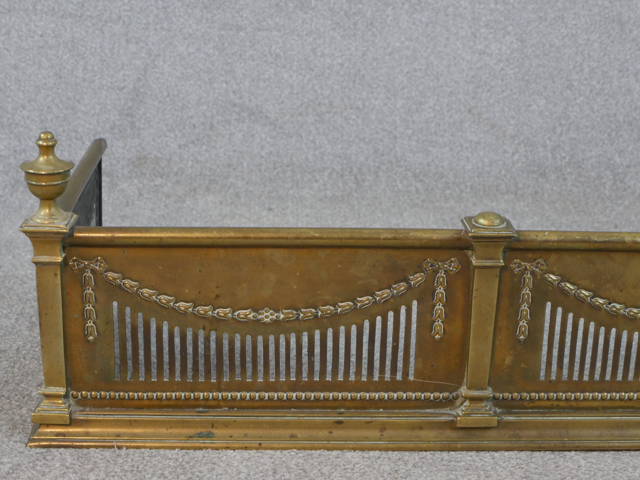 An Adam style pierced brass fender, with urn finials to the corners, decorated with swags and a - Image 4 of 4