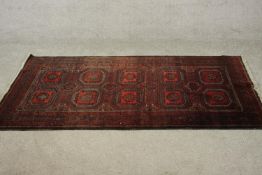 A Persian Meshed rug with repeating medallions on a burgundy ground within stylised flowerhead