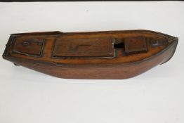 An early 20th century varnished treen novelty money box, as boat hull, removable cover and coin