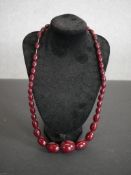 A vintage large cherry amber bakelite graduated bead necklace with screw barrel clasp. Weight 85g.