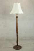 A 20th century stained beech standard lamp with a turned and reeded stem on a circular base, with