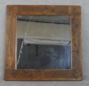 A large contempoary square hardwood framed wall mirror. Label verso. H.103 W.103cm