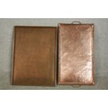 Two planished copper trays, one with two handles, the other with a chased floral border. L.64 W.